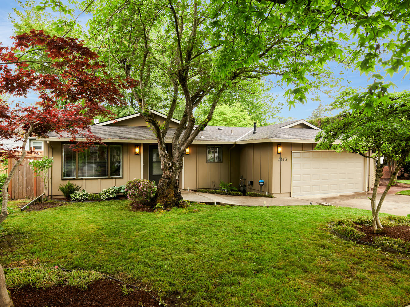 Exterior of house for sale in Portland Oregon in Laurelhurst with tree, grass and garage