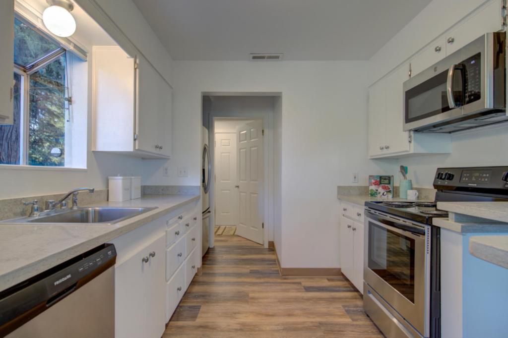 Kitchen with wood floors and counters on each side with a window over the sink on one side with a stove on the right side