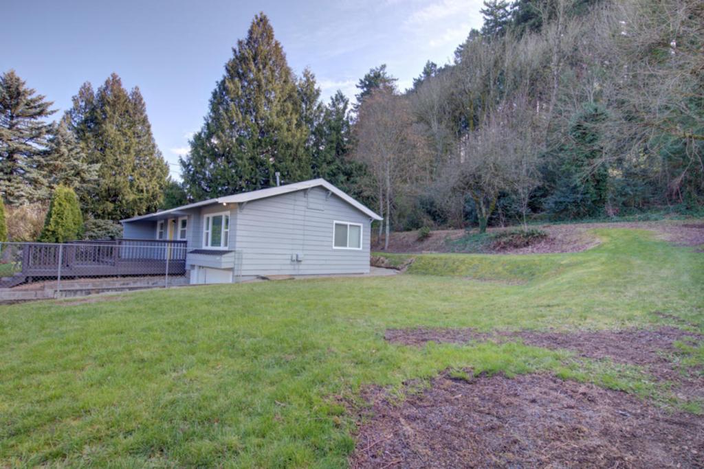 House with large green grassy yard and trees at the back
