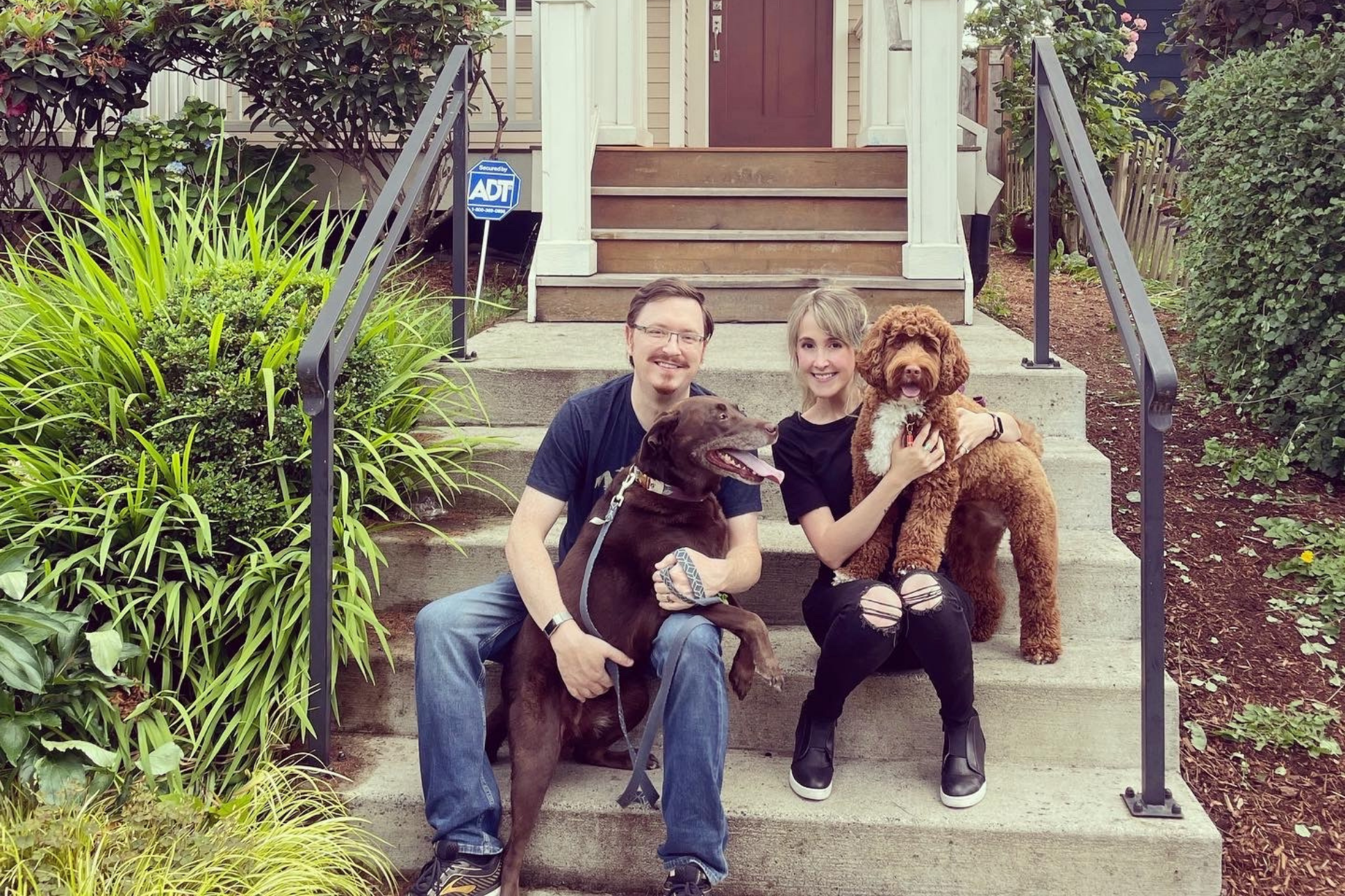 Keith and Sarah sitting on front steps holding their 2 dogs