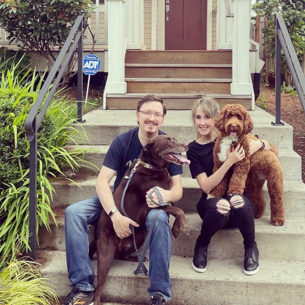 Keith and Sarah sitting on front steps holding their 2 dogs