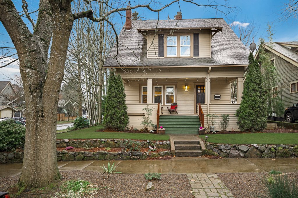 Exterior of a craftsman home with a front porch, green grass and a tree on the left