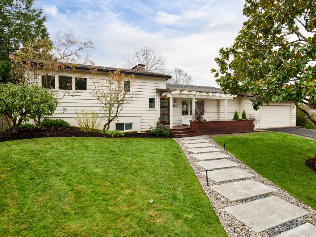 Exterior of midcentury home with concrete slap steps leading up to the front door under the covered porch