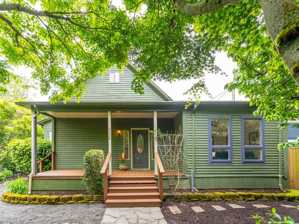 Green home exteror with steps up to covered front porch. Tree fringe at the top.