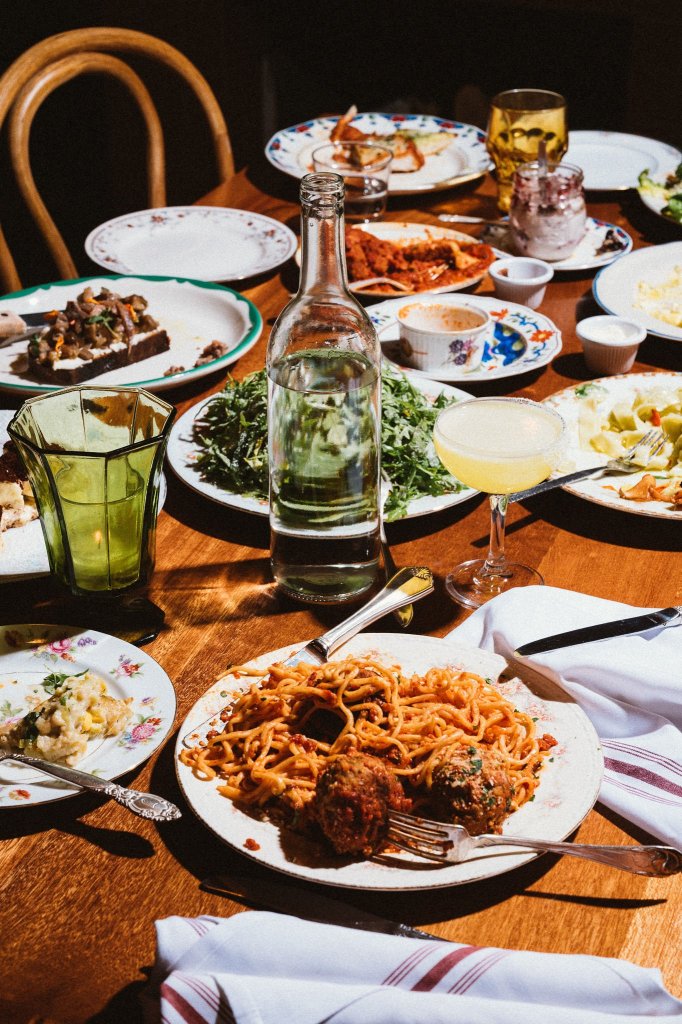 table top with a spread of various Italian food on top like pasta and salad and bruschetta