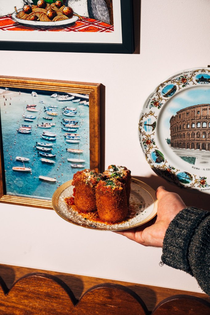 hand holding a plate of fried mozzarella