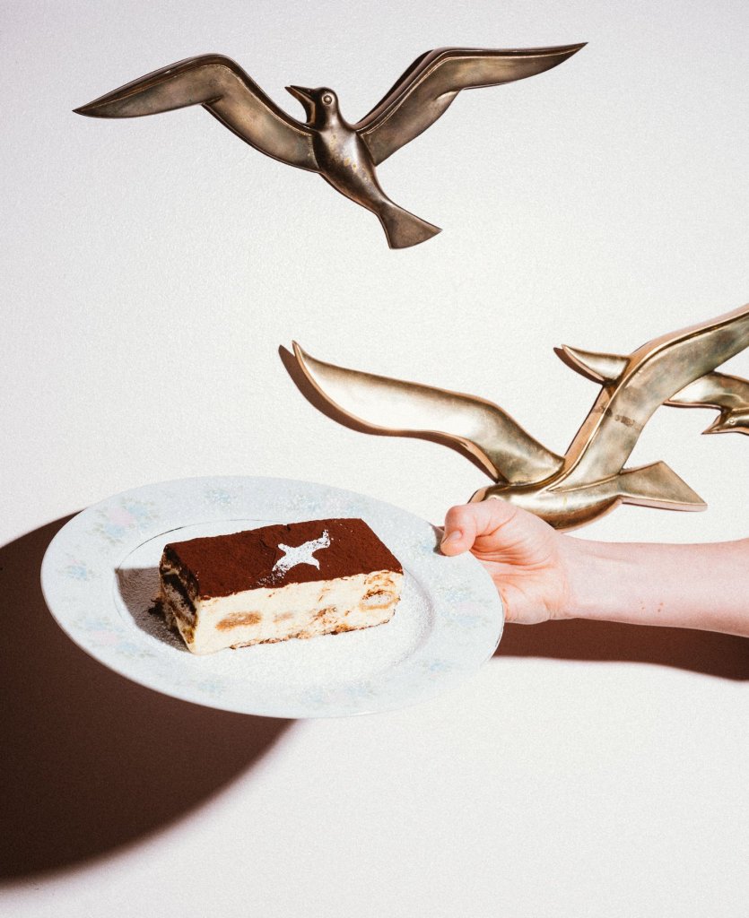 Handing holding a plate of tiramisu