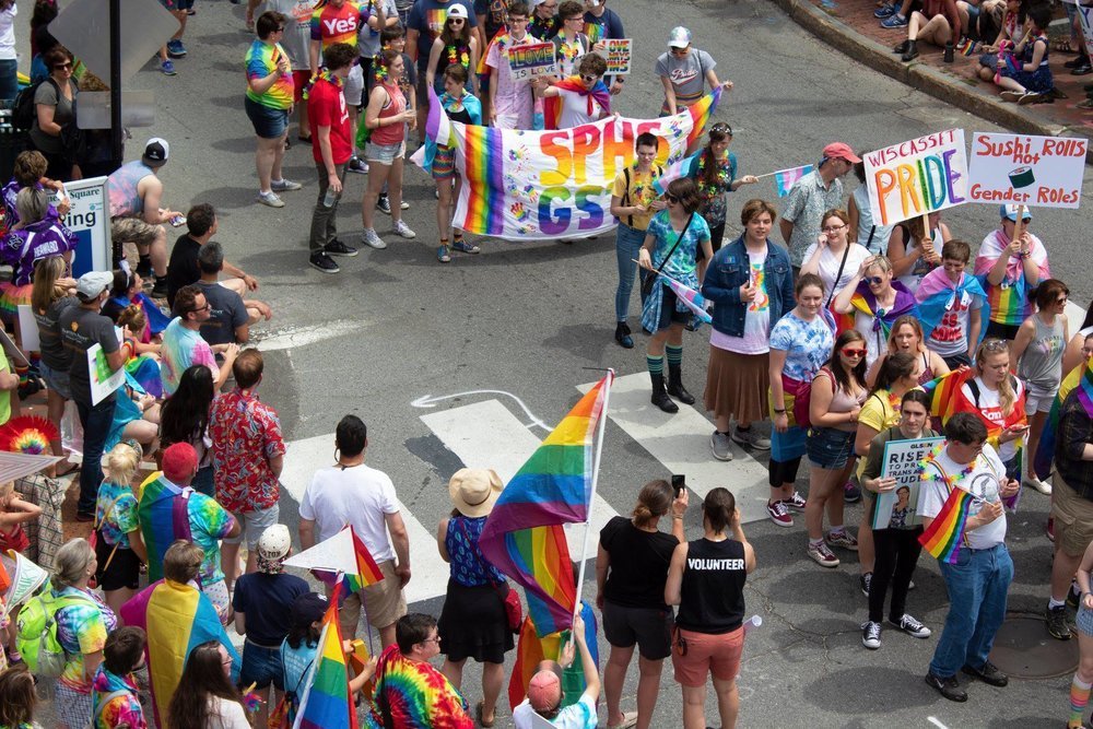 Crowds on the street at a pride parade with rainbow flags