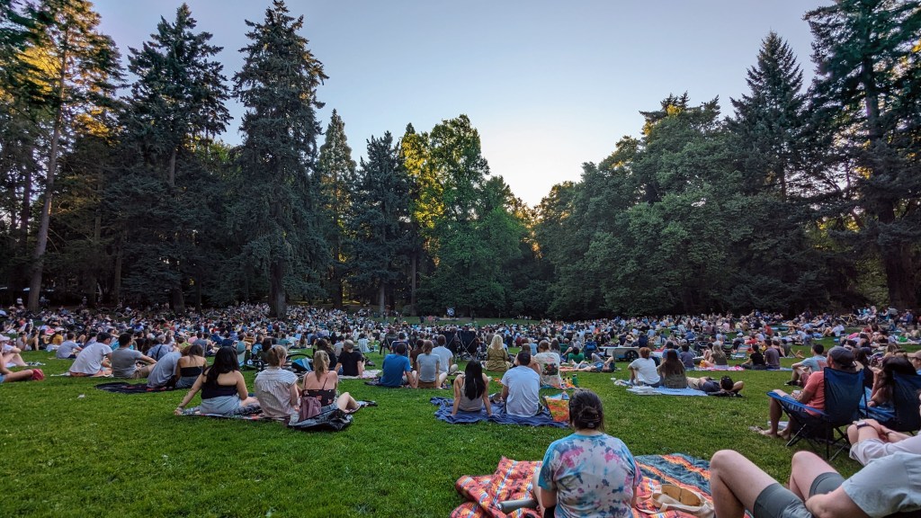 People gathered on blankets at Laurelhurst Park with trees in the background